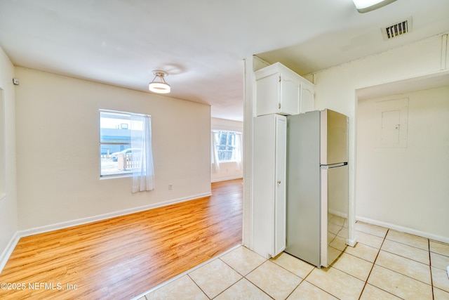 interior space featuring white cabinetry, light tile patterned floors, and stainless steel fridge