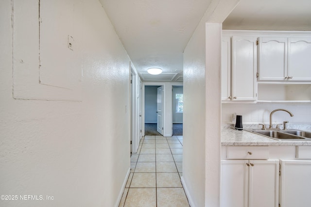 hall featuring sink, light tile patterned floors, and a textured ceiling