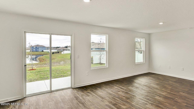 spare room featuring plenty of natural light, dark hardwood / wood-style flooring, and a textured ceiling