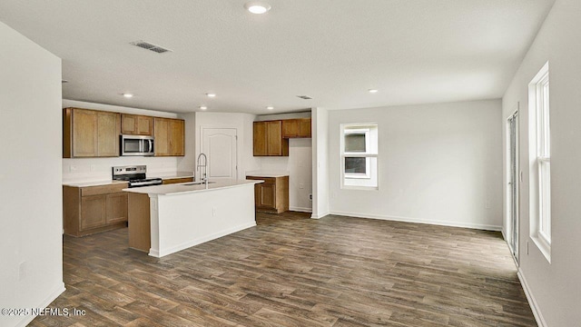 kitchen featuring a kitchen island with sink, sink, dark hardwood / wood-style floors, and appliances with stainless steel finishes