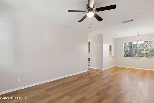 unfurnished room with ceiling fan with notable chandelier and light wood-type flooring