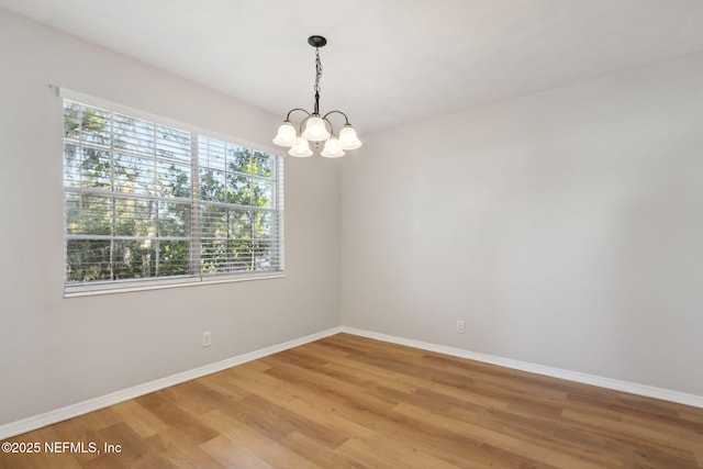 spare room featuring a chandelier and hardwood / wood-style flooring