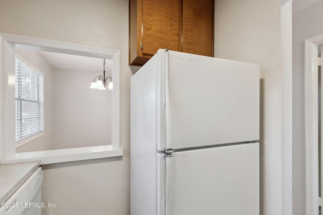 kitchen featuring pendant lighting, white appliances, and a notable chandelier