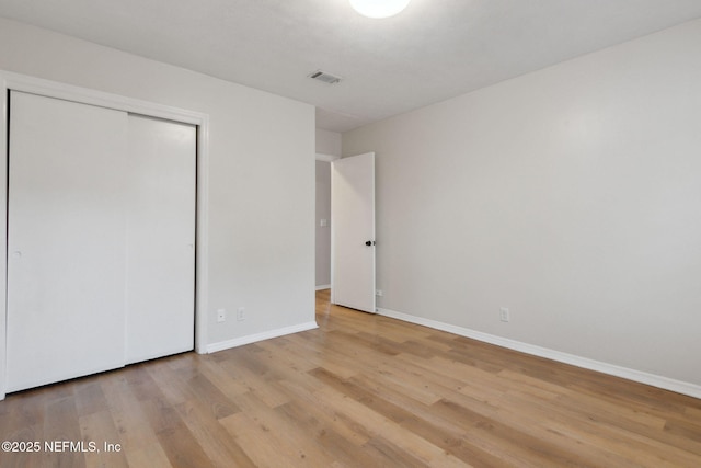 unfurnished bedroom with light wood-type flooring and a closet