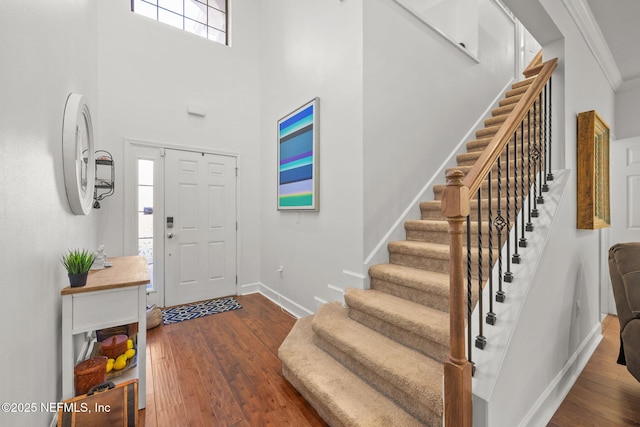 foyer entrance with dark hardwood / wood-style flooring, a towering ceiling, and ornamental molding