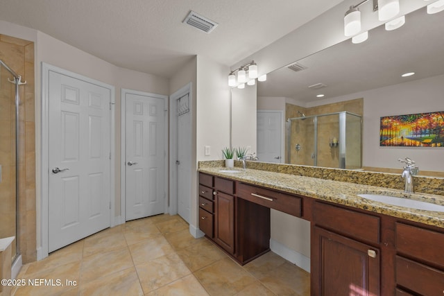 bathroom with tile patterned floors, a shower with door, vanity, and a textured ceiling