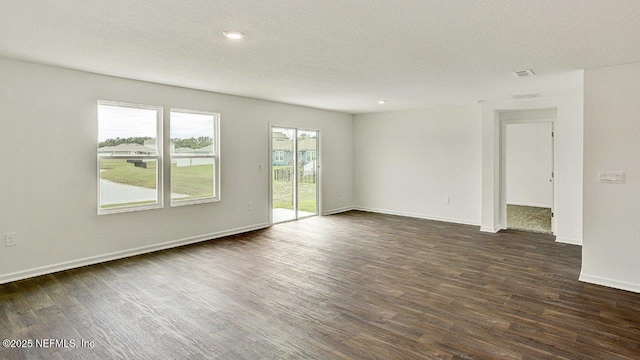 empty room with a textured ceiling and dark hardwood / wood-style floors