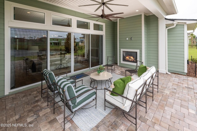 view of patio / terrace with an outdoor living space with a fireplace and ceiling fan