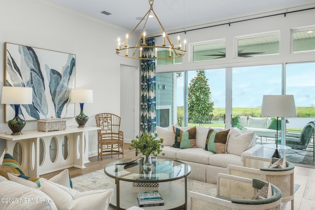 living room featuring a healthy amount of sunlight, a water view, light wood-type flooring, and an inviting chandelier