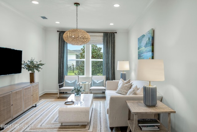 living room with a chandelier, light hardwood / wood-style floors, and ornamental molding