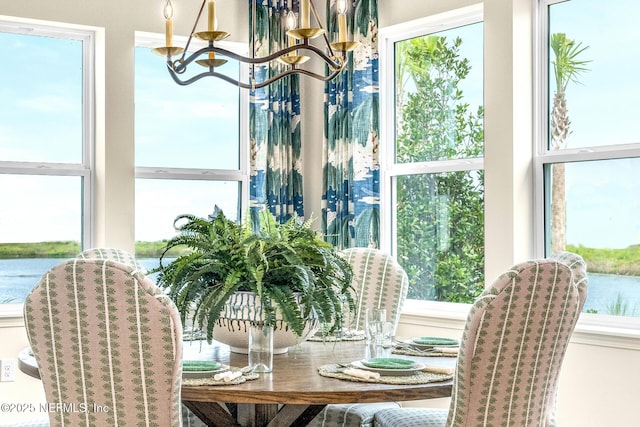 dining space featuring a water view and a notable chandelier