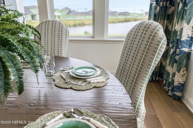 dining space featuring hardwood / wood-style floors and a water view