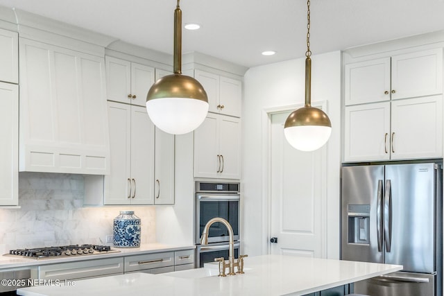 kitchen featuring pendant lighting, sink, tasteful backsplash, white cabinetry, and stainless steel appliances