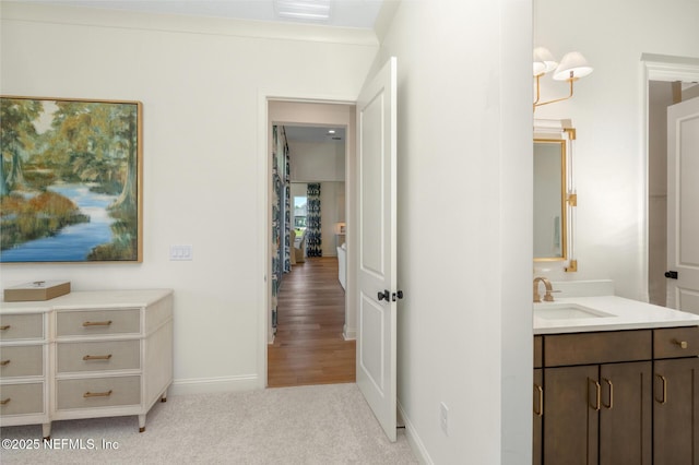 corridor featuring light colored carpet, ornamental molding, and sink