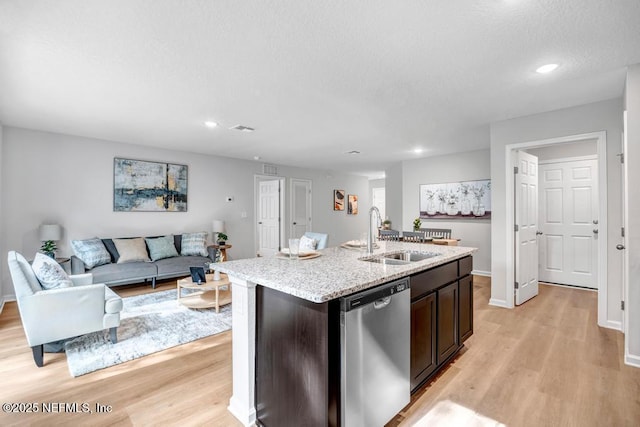 kitchen featuring sink, light hardwood / wood-style flooring, stainless steel dishwasher, a kitchen island with sink, and dark brown cabinets