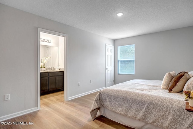 bedroom featuring a textured ceiling, light hardwood / wood-style floors, ensuite bath, and a closet