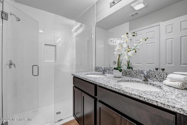 bathroom featuring vanity, an enclosed shower, and a textured ceiling