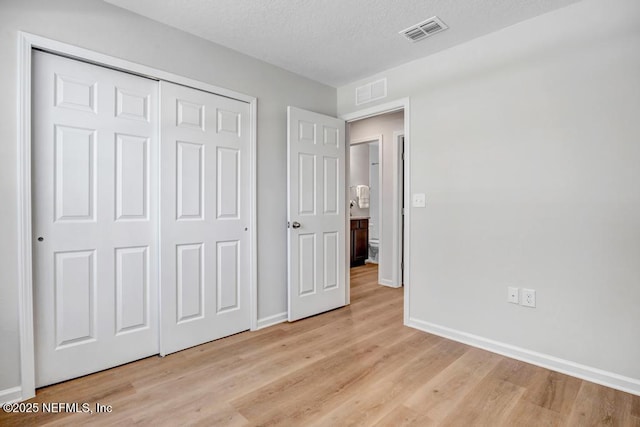 unfurnished bedroom with a textured ceiling, light hardwood / wood-style flooring, and a closet