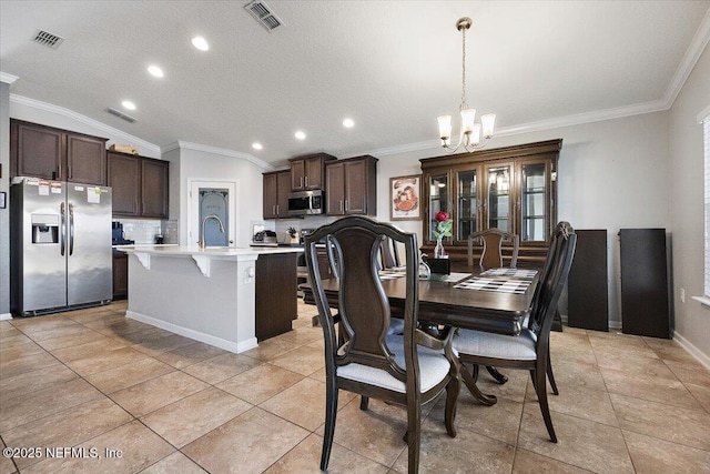 dining area featuring a chandelier, crown molding, lofted ceiling, sink, and light tile patterned flooring