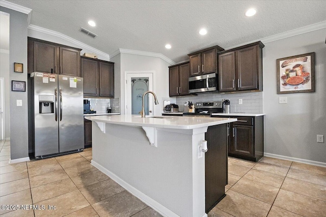 kitchen featuring lofted ceiling, decorative backsplash, a kitchen island with sink, and appliances with stainless steel finishes