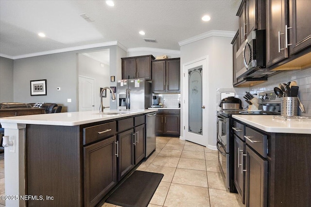 kitchen with stainless steel appliances, sink, light tile patterned floors, decorative backsplash, and a center island with sink