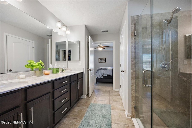 bathroom featuring tile patterned flooring, vanity, ceiling fan, a textured ceiling, and an enclosed shower