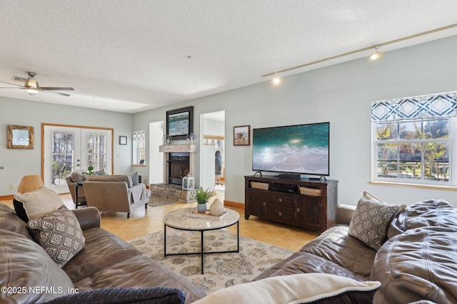 living room with rail lighting, a fireplace, a textured ceiling, french doors, and light parquet flooring