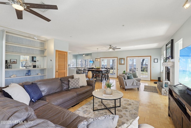 living room featuring french doors, ceiling fan, light parquet flooring, and a textured ceiling