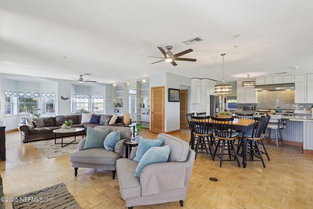 living room with light parquet flooring, a textured ceiling, and ceiling fan