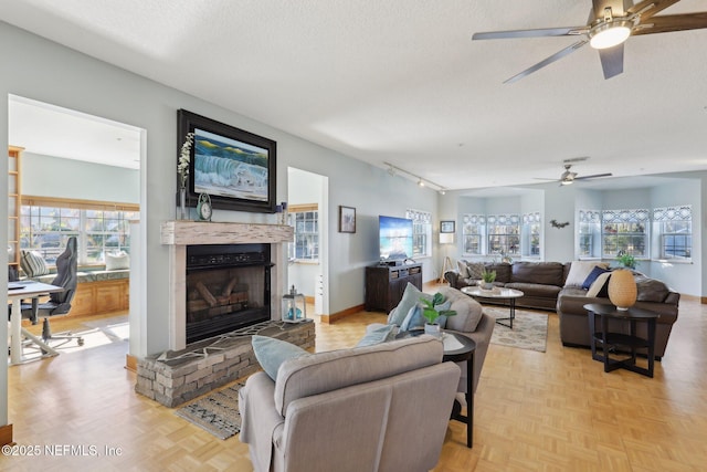 living room featuring a brick fireplace, track lighting, light parquet flooring, and a textured ceiling