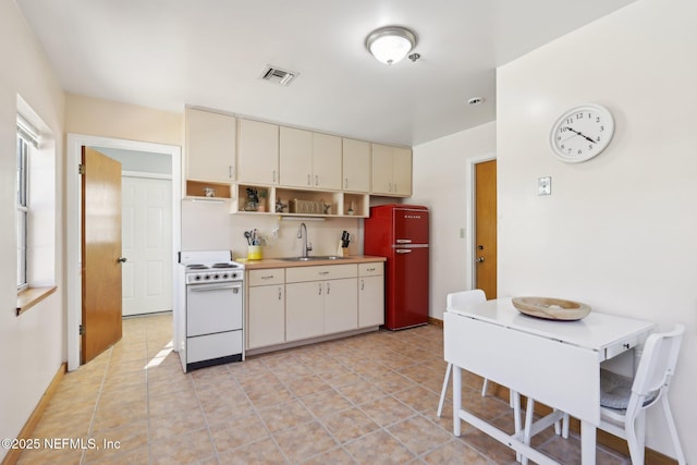 kitchen featuring sink, light tile patterned floors, cream cabinets, and white range with electric stovetop