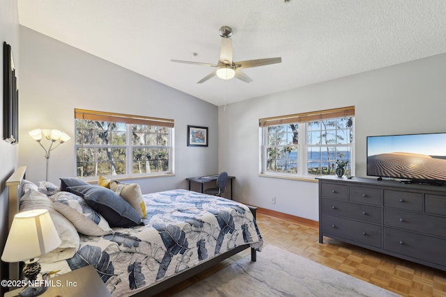 bedroom with ceiling fan, vaulted ceiling, multiple windows, and light parquet floors