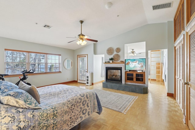 bedroom featuring ceiling fan, lofted ceiling, a fireplace, and light parquet floors