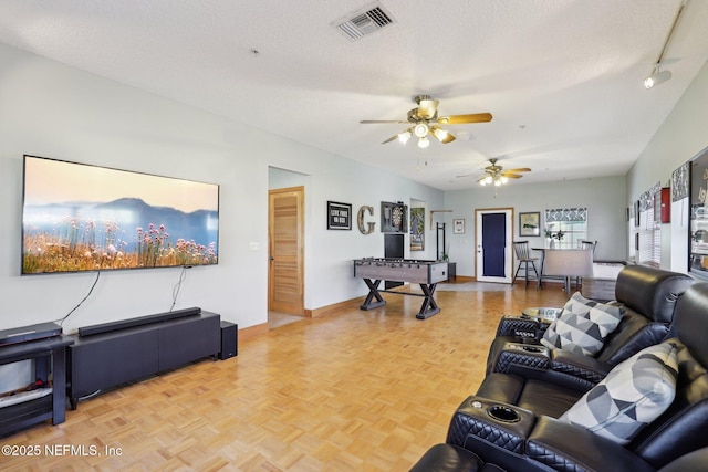 living room with ceiling fan, parquet flooring, and a textured ceiling