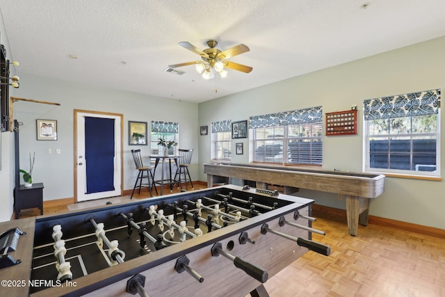 recreation room featuring light parquet flooring, a textured ceiling, and ceiling fan