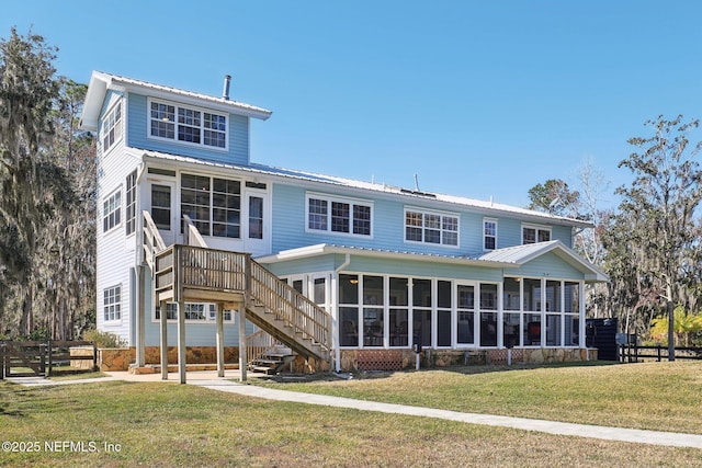 rear view of property featuring a sunroom and a yard