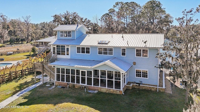 rear view of house featuring a sunroom and a lawn