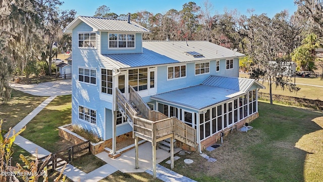 rear view of house with a sunroom and a lawn