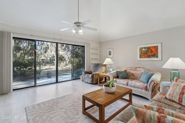 living room with ceiling fan, light hardwood / wood-style floors, and vaulted ceiling