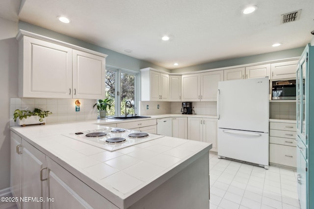 kitchen with white cabinetry, sink, white appliances, and kitchen peninsula