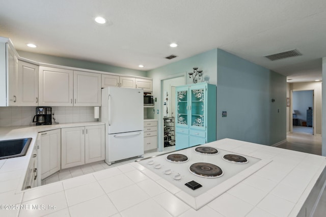 kitchen featuring backsplash, white appliances, light tile patterned floors, tile countertops, and white cabinets