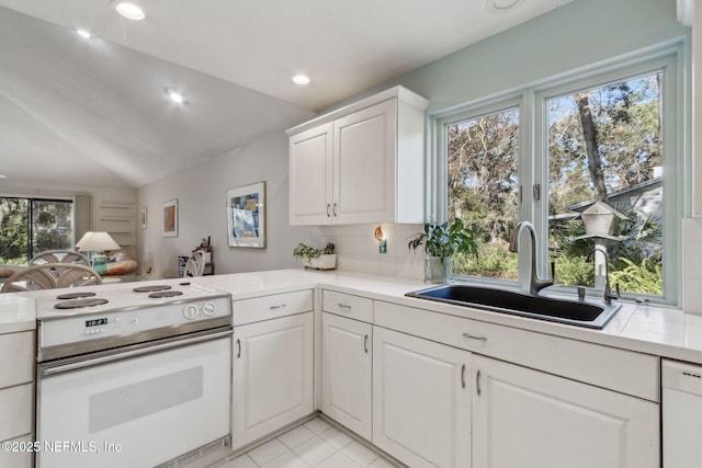 kitchen featuring white appliances, white cabinets, sink, vaulted ceiling, and a healthy amount of sunlight