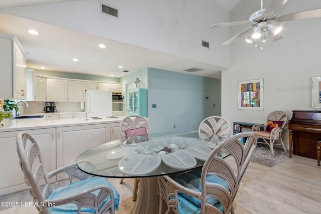 dining area featuring light wood-type flooring, vaulted ceiling, ceiling fan, and sink