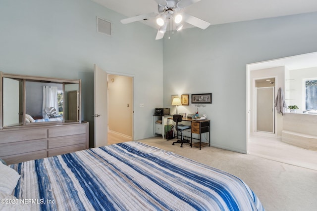 carpeted bedroom with connected bathroom, ceiling fan, and a towering ceiling