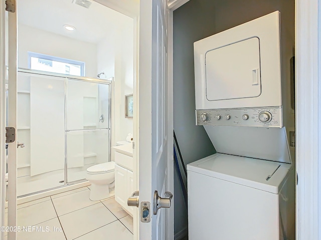 clothes washing area with stacked washing maching and dryer and light tile patterned floors