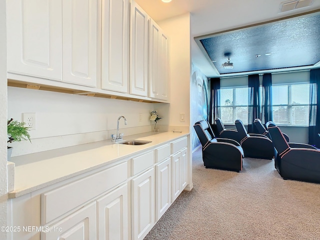 kitchen featuring light carpet, sink, and white cabinets