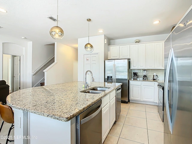 kitchen with white cabinets, sink, stainless steel appliances, and an island with sink