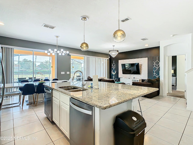 kitchen featuring white cabinets, decorative light fixtures, sink, and an island with sink