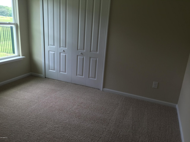 unfurnished bedroom featuring carpet floors, a closet, and multiple windows