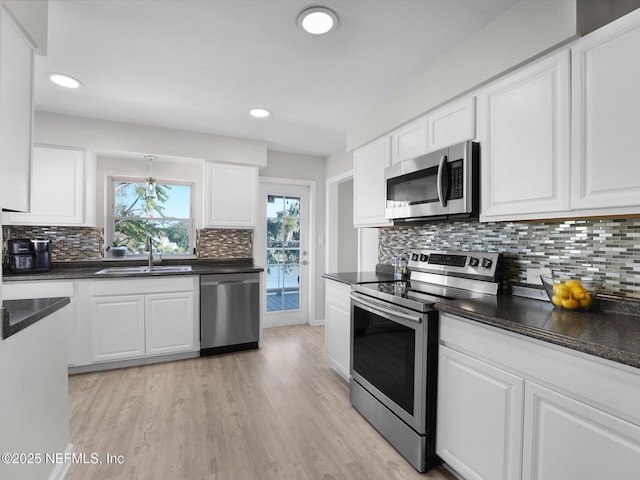 kitchen with stainless steel appliances, white cabinetry, sink, and light hardwood / wood-style floors